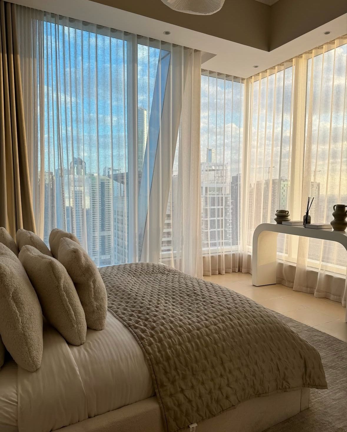 Luxury bedroom with floor-to-ceiling windows overlooking city skyline