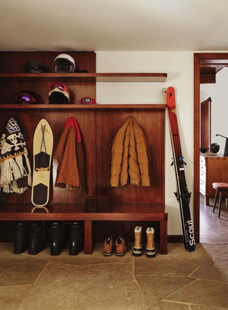 Rustic ski mudroom with wooden storage and winter gear