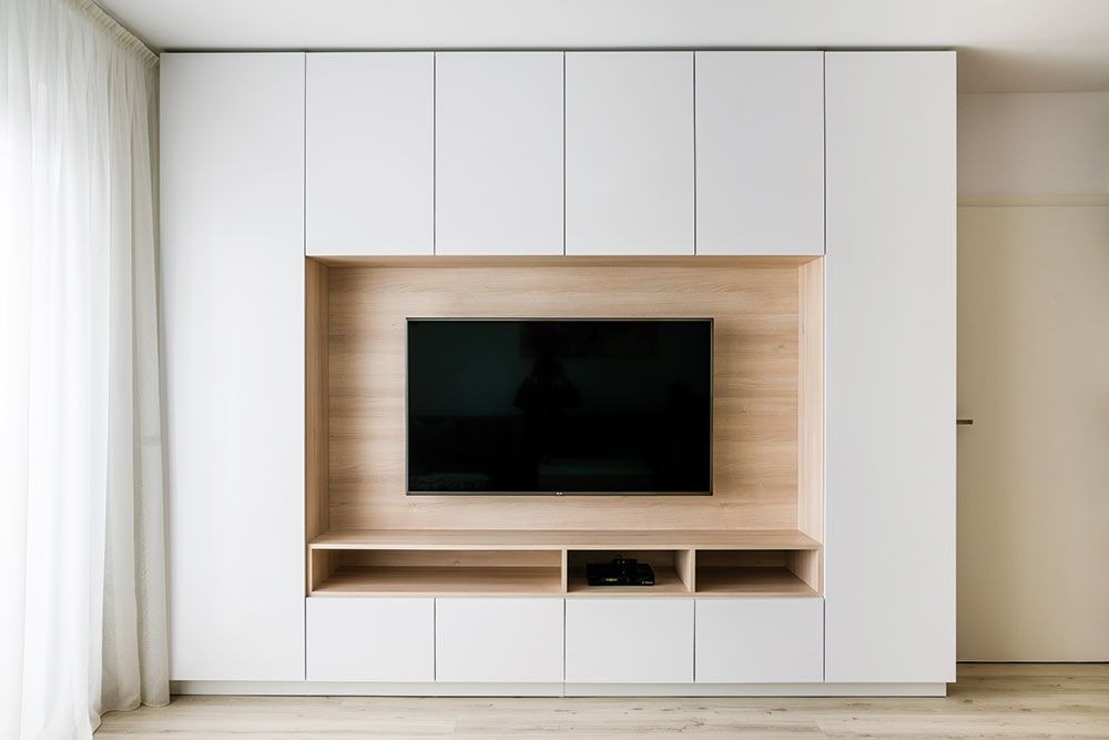 Modern built-in TV wall with white cabinets and wood accents