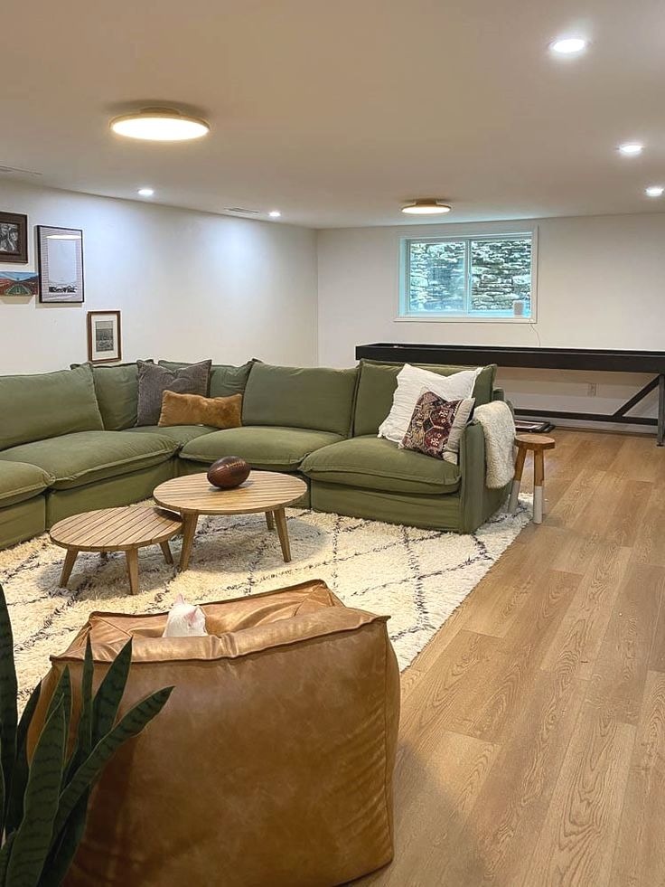 Cozy basement living room with green sectional and warm lighting